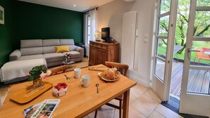 Un salon chaleureux avec un canapé, une table en bois sur laquelle sont disposés des éléments pour le petit-déjeuner, et un téléviseur posé sur un meuble.
