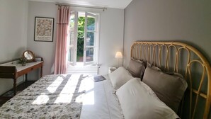 Une chambre à coucher avec un lit, une table de chevet, une lampe et une fenêtre avec des rideaux.