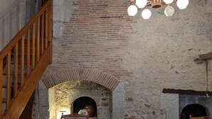 A rustic dining area with a brick fireplace, wooden staircase, and a chandelier. - Charming Cottage with WiFi and Pets Allowed (Saint-Romain)
