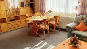 Un salón acogedor con una mesa de comedor, sillas, un sofá y una estantería.