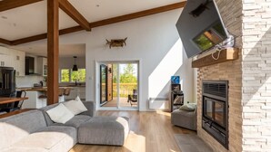 Een moderne woonkamer met een hoekbank, een open haard en een keuken op de achtergrond.