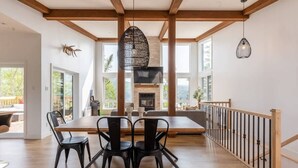 Een eetgedeelte met een houten tafel en stoelen, een hanglamp en uitzicht op de omgeving.