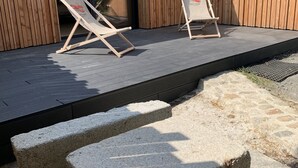 Un área de estar al aire libre con dos sillones y una mesa de piedra.