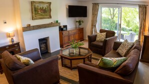 Una sala de estar con chimenea, televisión y un conjunto de sofás.