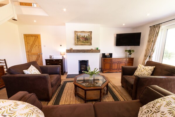 A living room with brown sofas, a glass coffee table, a fireplace, a mounted TV, and a wooden door.
