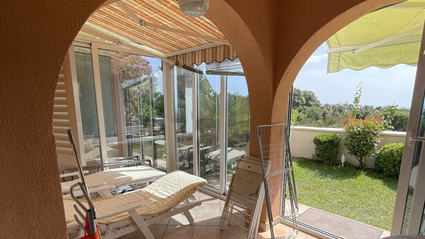 A sunlit patio area with a glass enclosure, a metal chair, and a table. - Exclusive Apartment Sun and Sea  (Novalja)