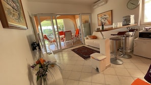 A modern living room with a white sofa, a small table, and a kitchen area with a microwave and a sink. - Exclusive Apartment Sun and Sea  (Novalja)