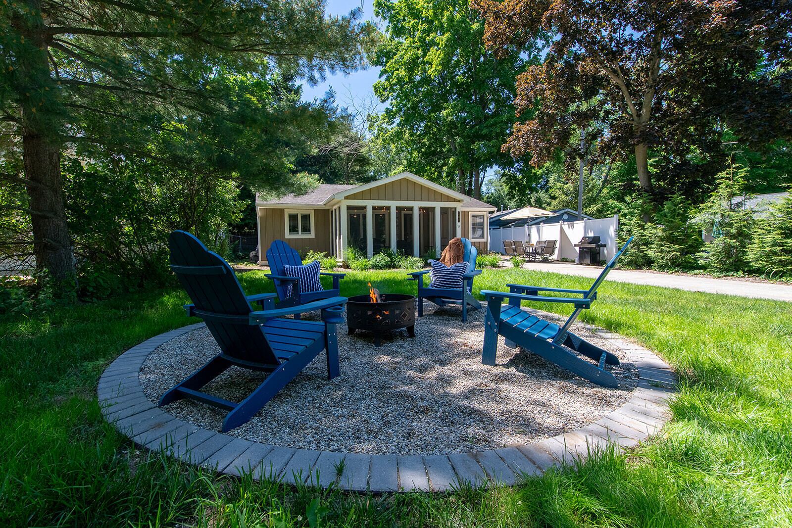 Un espacio al aire libre con asientos circulares, sillas tipo Adirondack, un hogar a la vista y una chimenea.