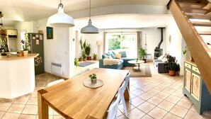 A spacious living area with a wooden dining table, a blue sofa, and a kitchen area with a refrigerator and a stove. - Beautiful bask villa close to Bidart Guethary Biarritz beaches (Ahetze)