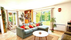 A living room with a sectional sofa, a coffee table, a bookshelf, and a large window. - Beautiful bask villa close to Bidart Guethary Biarritz beaches (Ahetze)