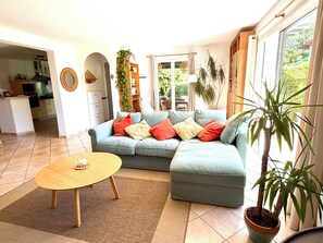 Una sala de estar con un sofá modular, una mesa de centro de madera y una planta en maceta.