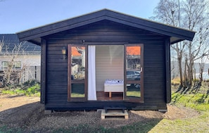 A small wooden cabin with a single door and a small step leading up to it.