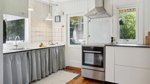 A modern kitchen with white cabinetry, stainless steel appliances, a large window, and a view of greenery outside. - 2 bedroom gorgeous home in Askeby (Askeby)