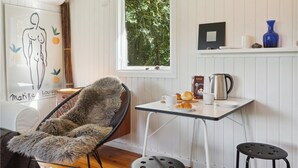 A cozy room with a wicker chair, a small table with a kettle, and a window with a view of trees. - 2 bedroom gorgeous home in Askeby (Askeby)