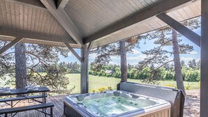 A covered outdoor area with a hot tub, picnic table, and dining setup. - Luxury Lodge on Golf Course with Private Hot Tub, Pool & Gym Access (Le Chambon-sur-Lignon)