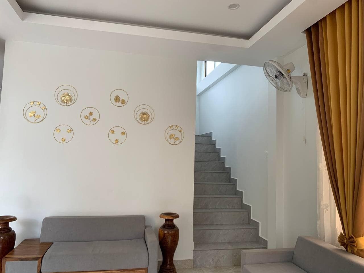 A modern living room with a grey sofa, a wooden coffee table, and a staircase leading to an upper floor.