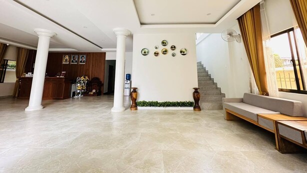 A spacious living area with a high ceiling, a staircase, and a seating area. - Laluna Guesthouse (Siem Reap)