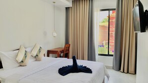 A hotel room with a large bed, a wooden chair, a small table, and a TV mounted on the wall. - Laluna Guesthouse (Siem Reap)