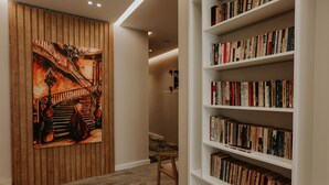 Un pasillo con pared de paneles de madera, una escalera con barandilla y una estantería llena de libros.