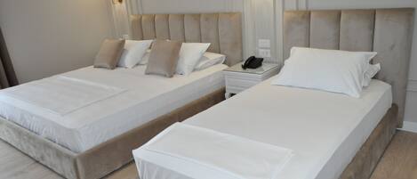 A hotel room with two beds, each with a headboard and bedside tables.