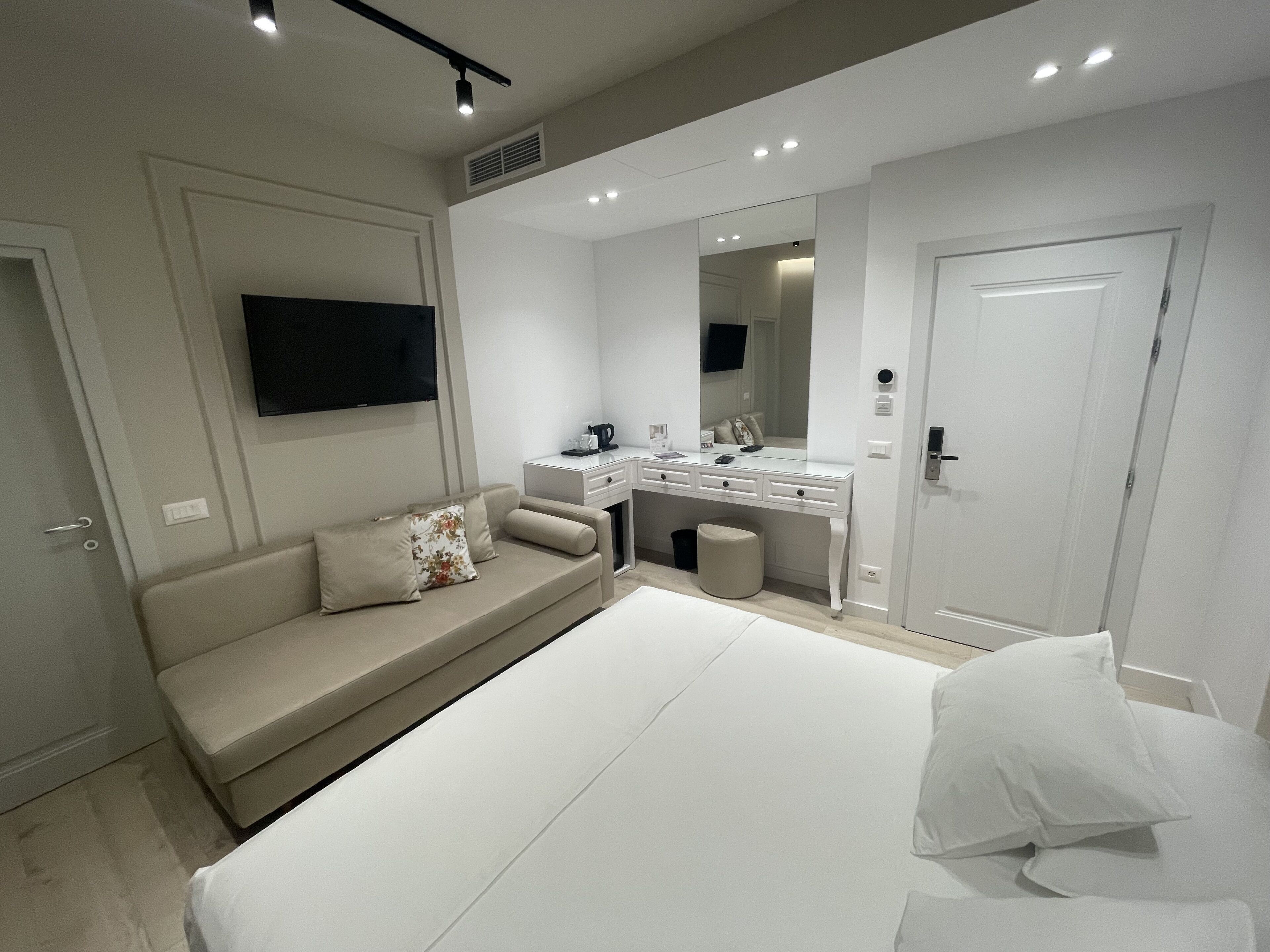 Un dormitorio moderno con cama, sofá, escritorio y televisor.