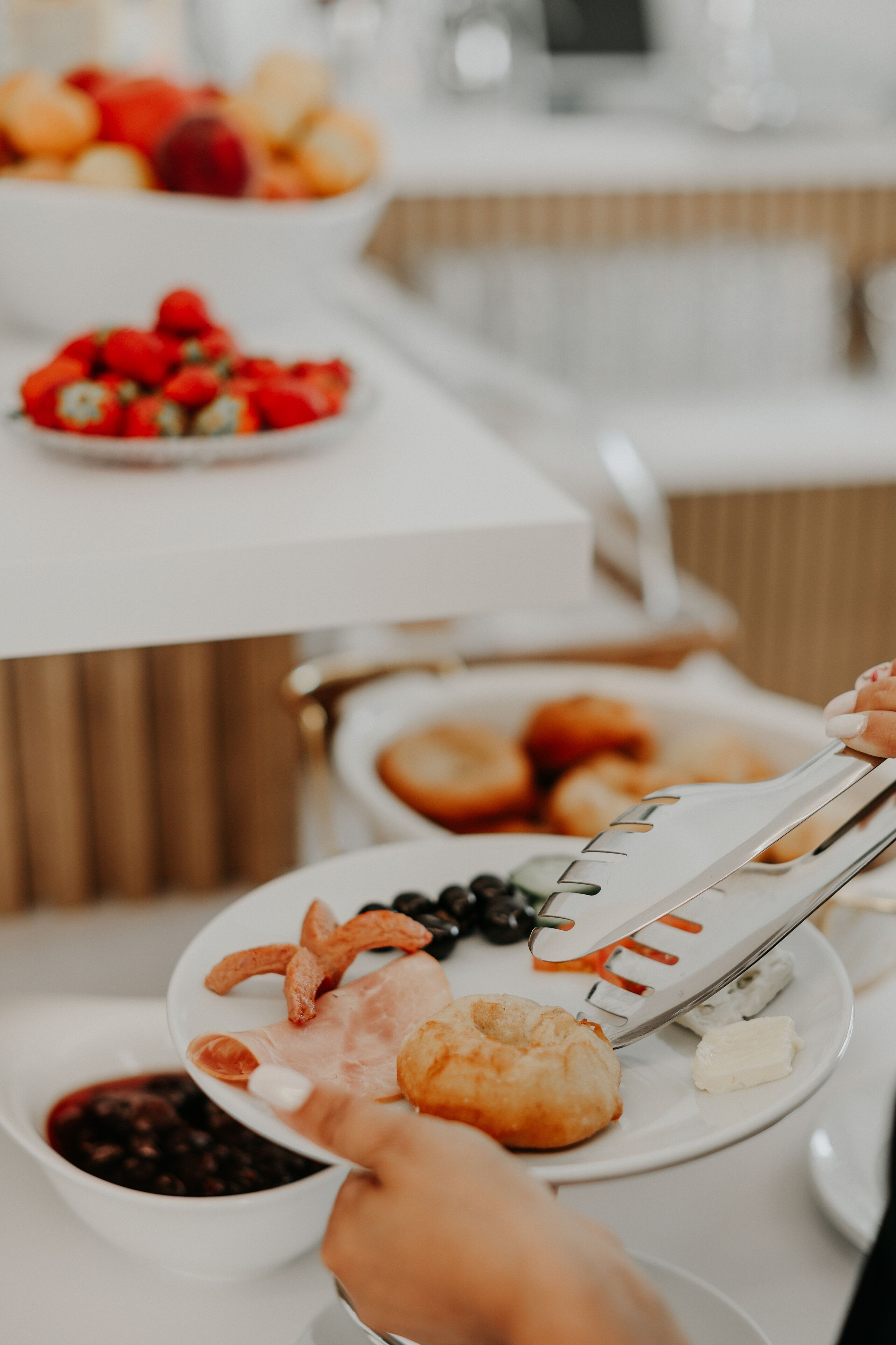 A buffet table with various food items including fruits, pastries, and a bowl of soup.