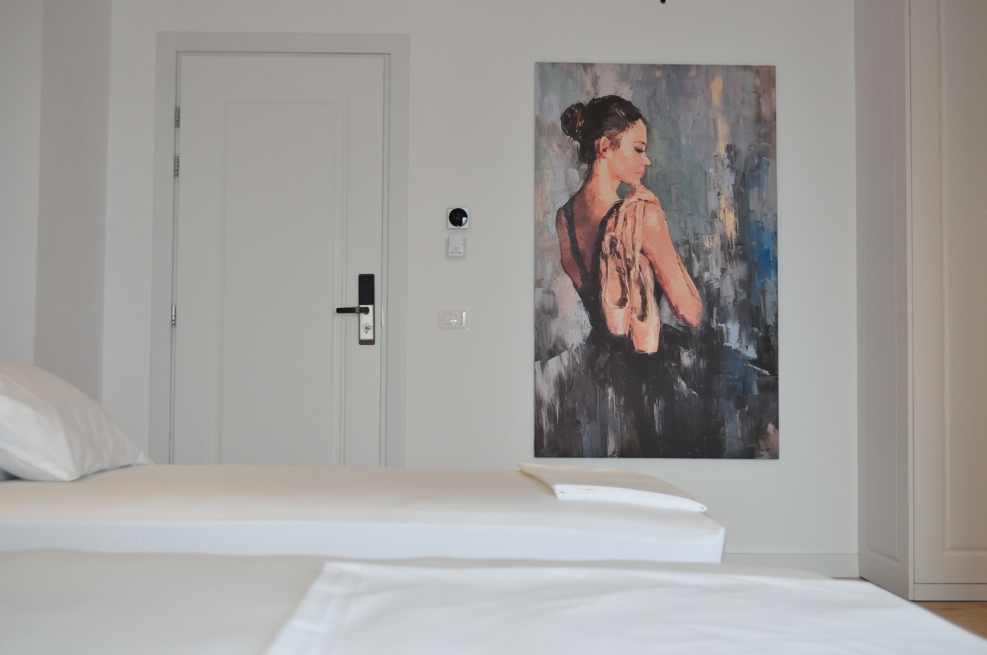 A bedroom with a bed, a door, and a painting on the wall.