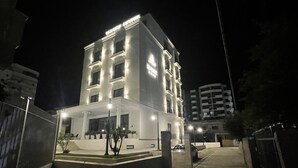 Un hotel de varios pisos con una entrada destacada y señalización iluminada.