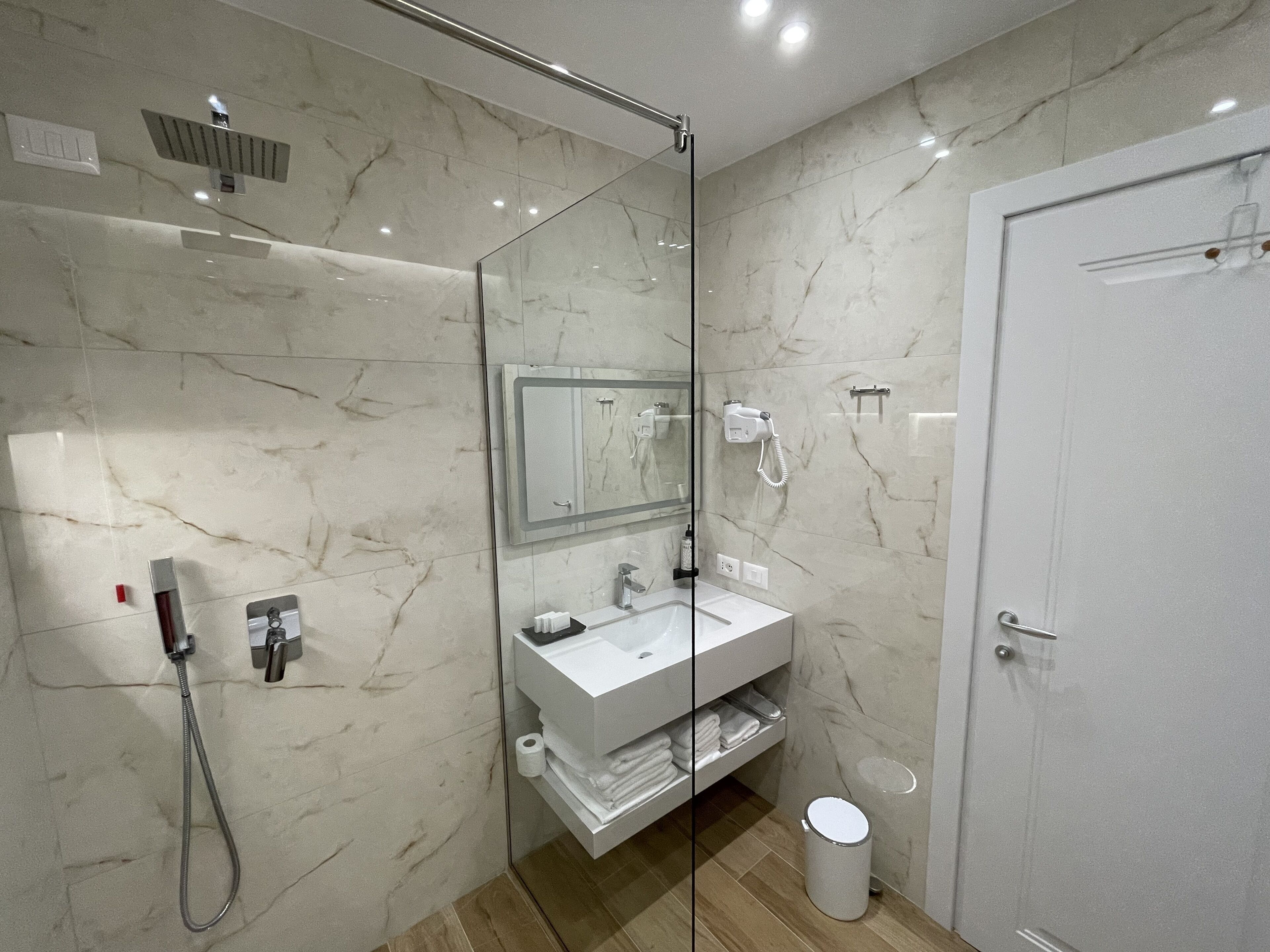 A modern bathroom with a glass-enclosed shower, a white sink, and a large mirror.