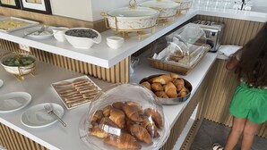 Montaje de bufé con diversas opciones de comida, incluyendo un bol de croissants y un recipiente con arándanos.