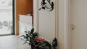 Un pasillo con un panel de madera a listones, una obra de arte abstracta negra y plantas en macetas.