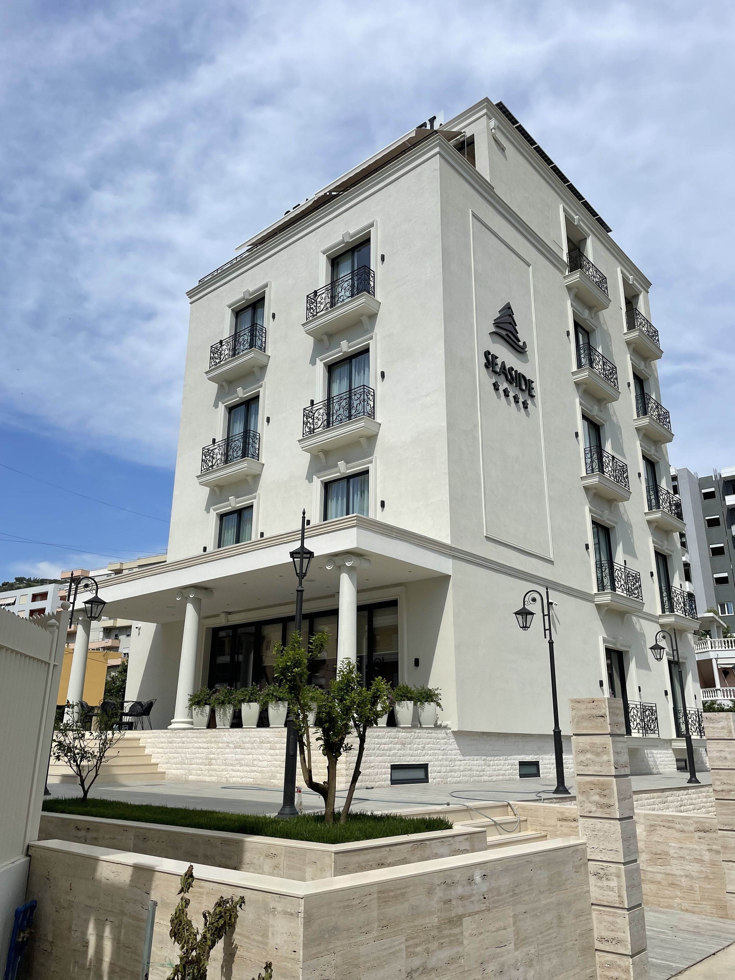 A multi-story hotel with a white facade, balconies with wrought iron railings, and a sign reading "SEASIDE".