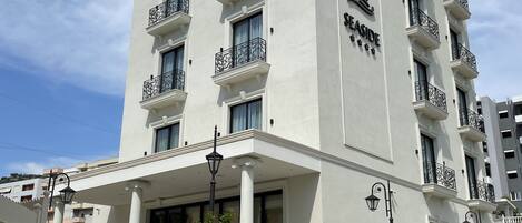 A multi-story hotel with a white facade, balconies with wrought iron railings, and a sign reading "SEASIDE".