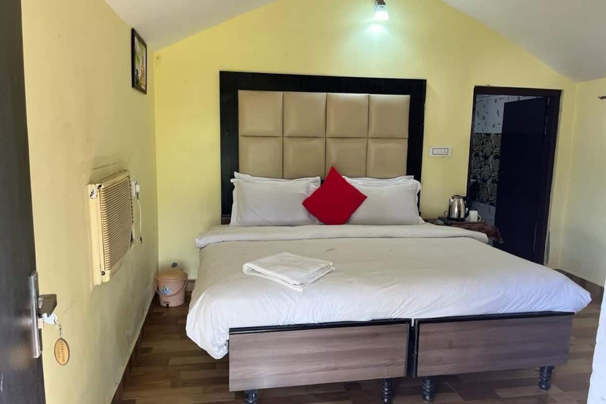 Una cama bien hecha con cabecera, mesita de noche y velador.