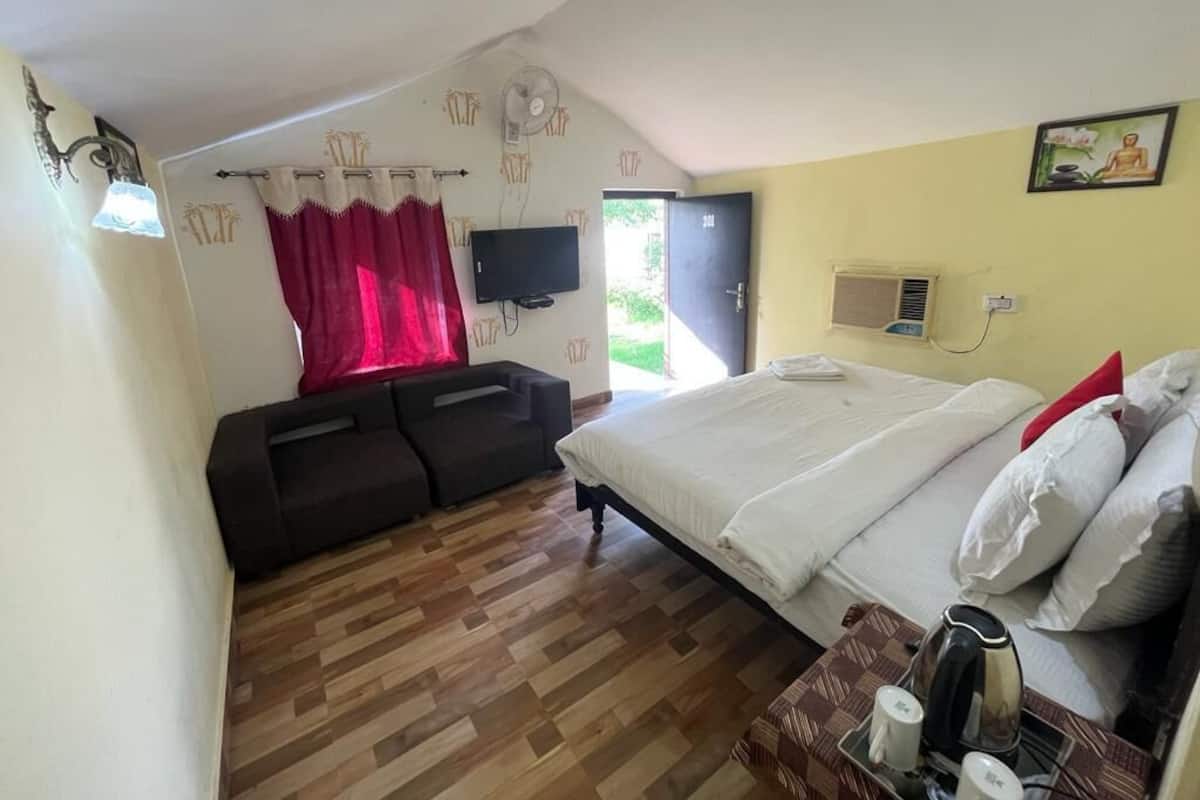 Una habitación con cama, sofá, televisión y ventana con cortinas.