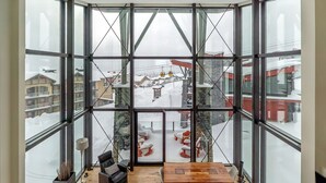 A spacious room with large windows, a wooden floor, a central table, and a sofa.