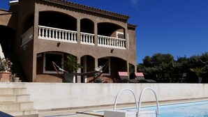 En toetagers bygning med balkon, swimmingpool og udendørs møbler.