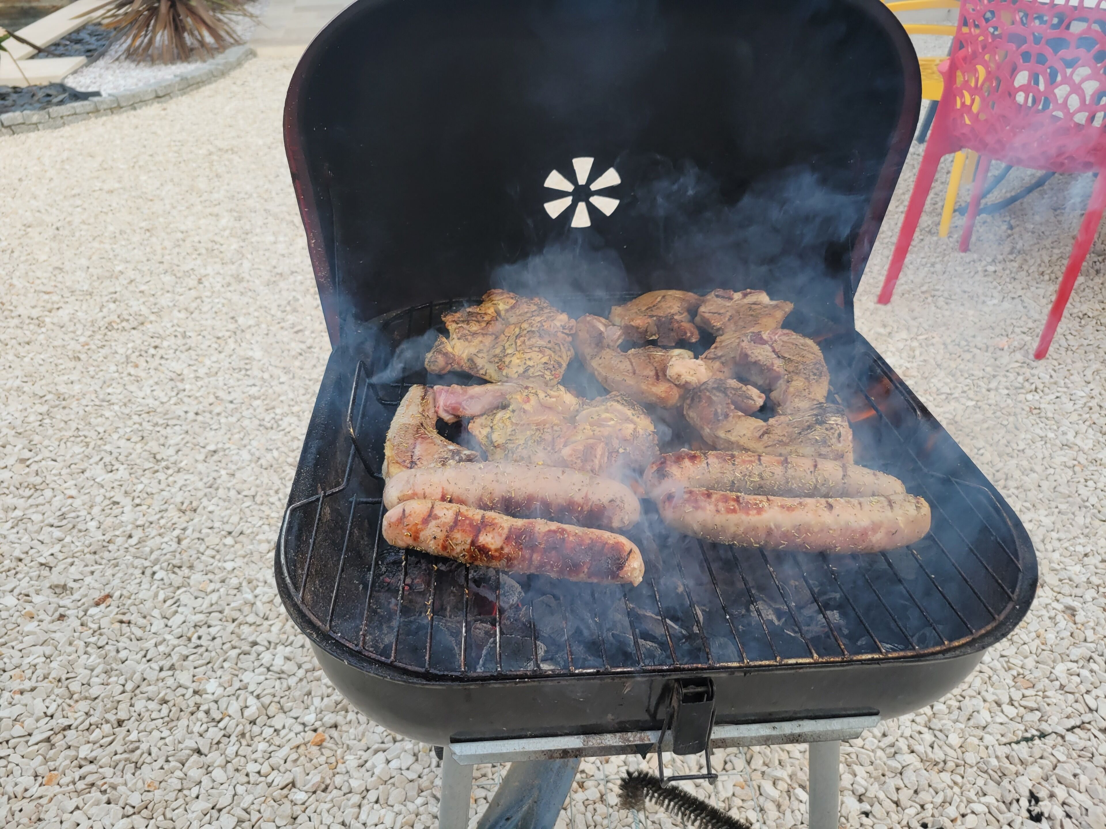 Un barbecue avec différentes sortes de viande en train de cuire.