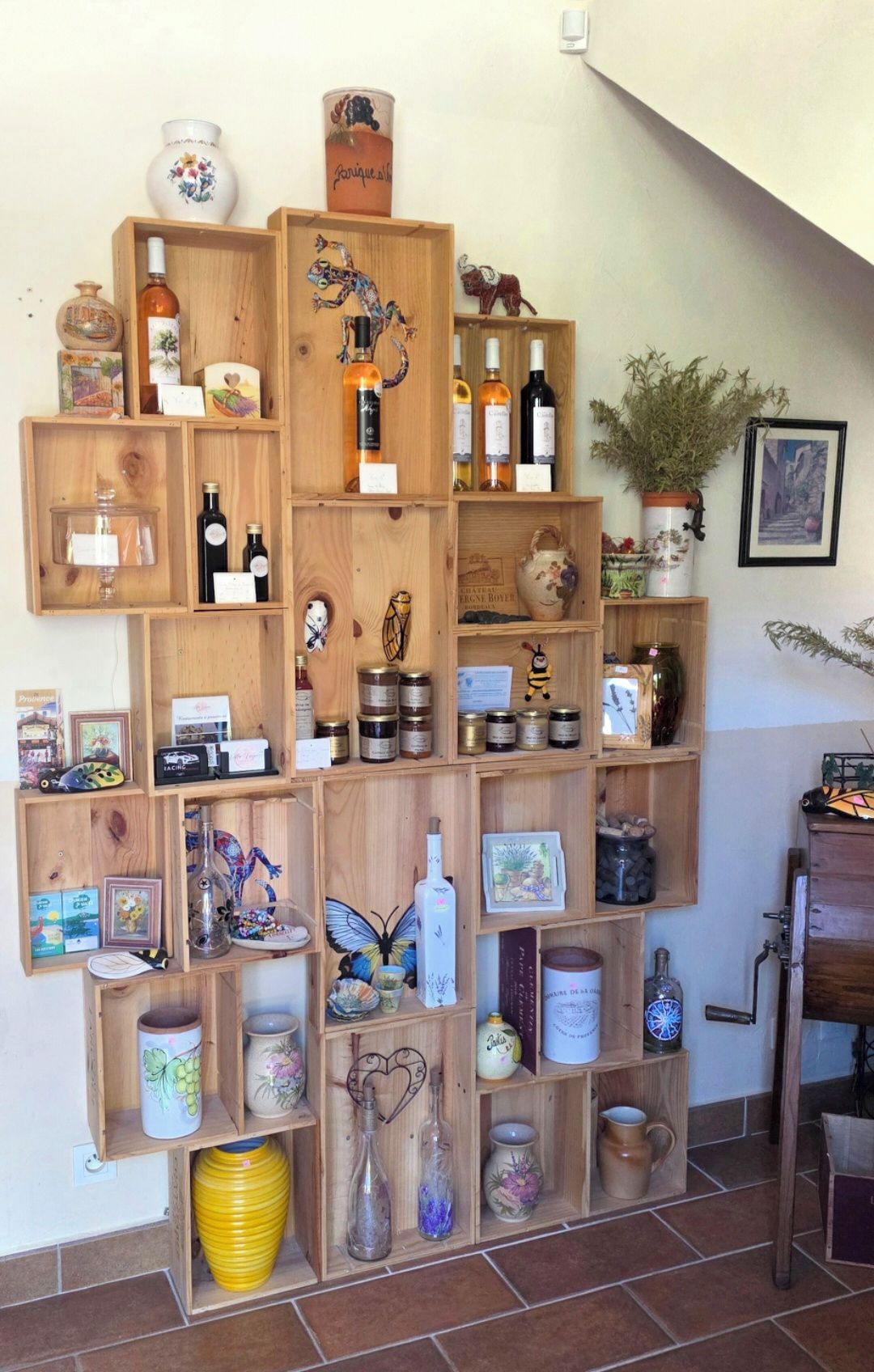 A wooden display shelf with various items including bottles, jars, and decorative objects.