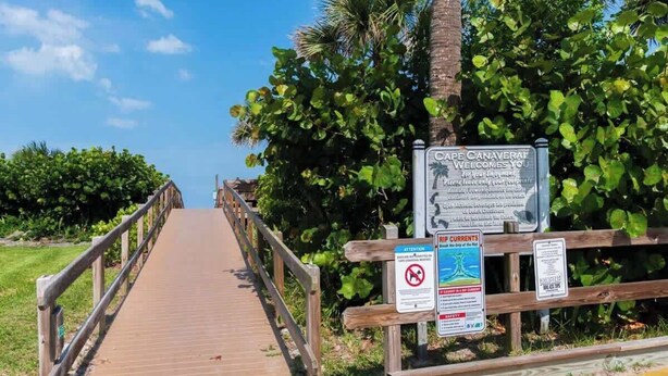 Une promenade en bois mène à une plage, et un panneau accueille les visiteurs à Cap Canaveral.
