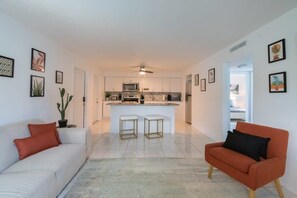 Ein modernes Apartment mit Küche, zwei Sitzbereichen und einem Essbereich.