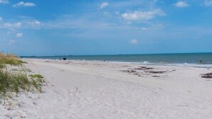 Une plage avec du sable, la mer et un ciel dégagé.