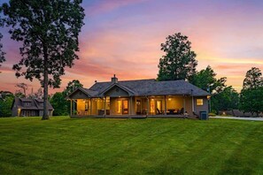 A two-story house with a porch and a covered front porch area, surrounded by a well-maintained lawn and trees.