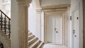 A staircase with a white door at the top, leading to a room with a white wall and a door with a sign above it.