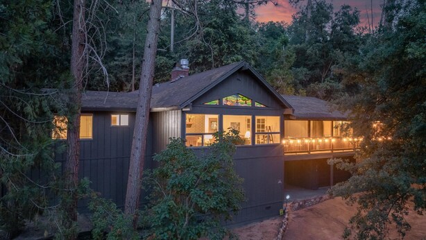 A cabin with a large window, a balcony, and a view of the surrounding forest. - Sierra Mountain Escape - Brand new spa/game room! (Oakhurst)