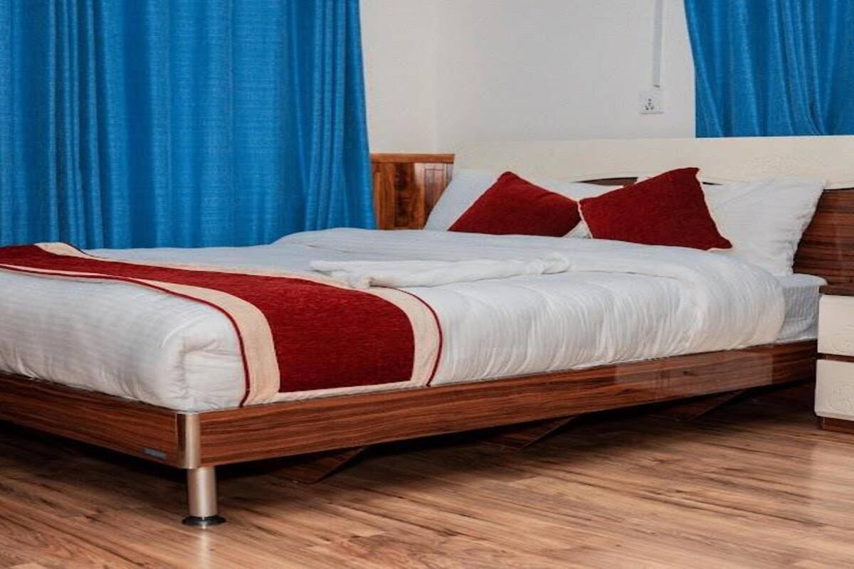A neatly made bed with a wooden frame, white bedding, and red accents.