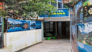 Entrada de un hotel con un letrero que dice "HOTEL EL ORANA" y un mural que representa un paisaje montañoso.