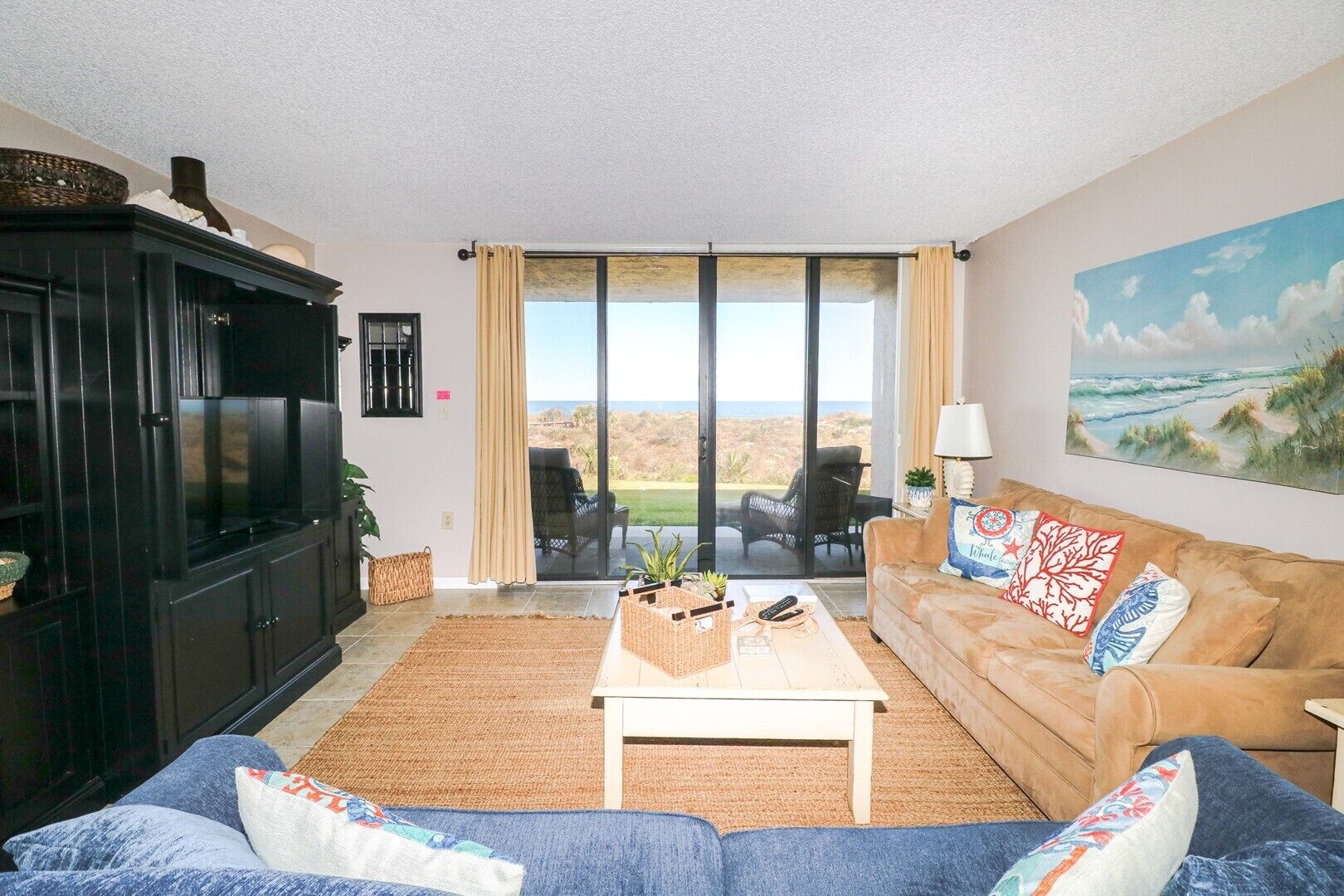 A living room with a large window, a sofa, a coffee table, and a television.