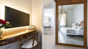 A hotel room with a large mirror, a bedside table with a vase of flowers, a bed with white bedding, and a bathroom visible through the mirror. - Villa Savioli (Bologna)