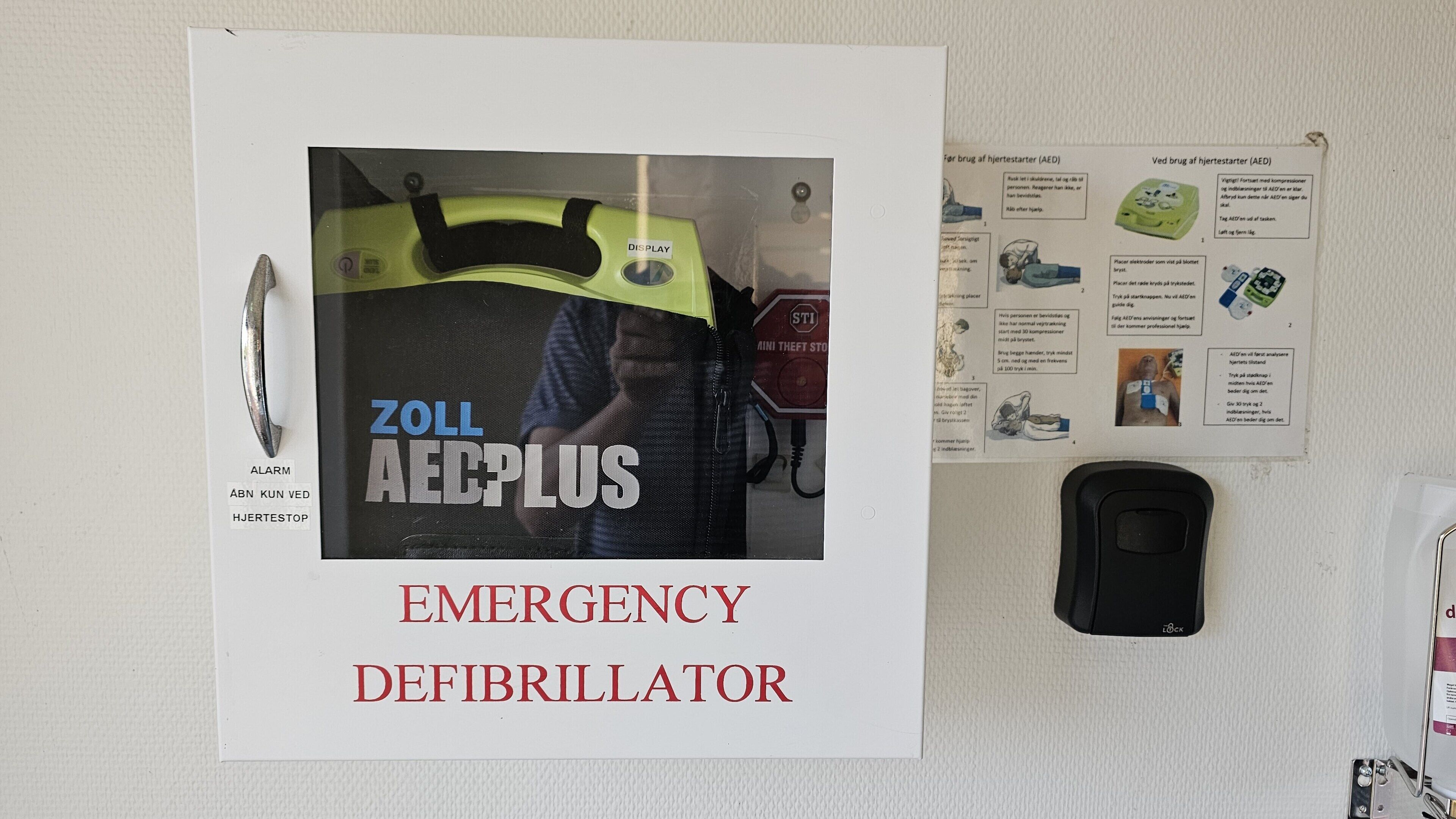 A wall-mounted emergency defibrillator labeled 'ZOLL AEDPLUS' with a display screen and a control panel.